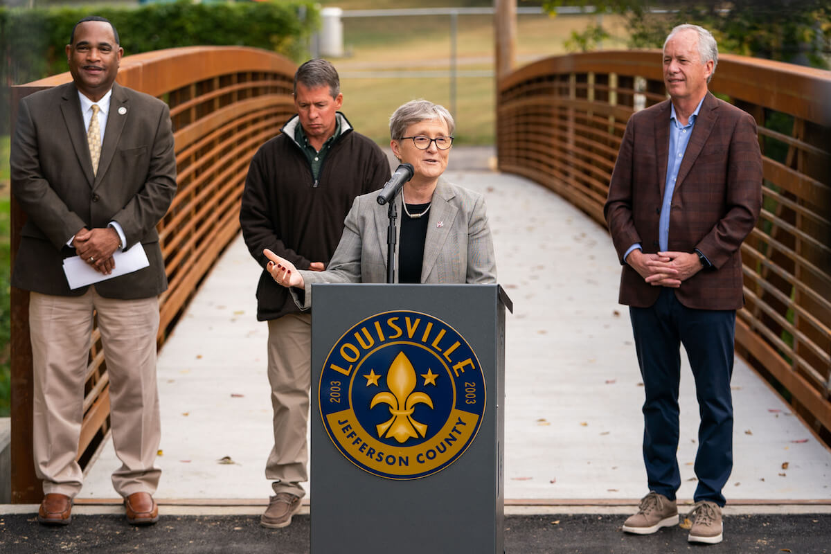 Four people standing on a bridge with a podium