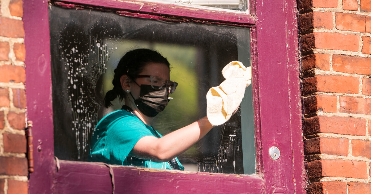 A student wearing a mask washing windows
