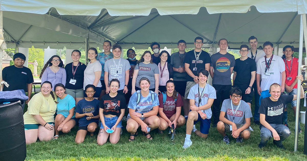A large group of people posing under a big tent