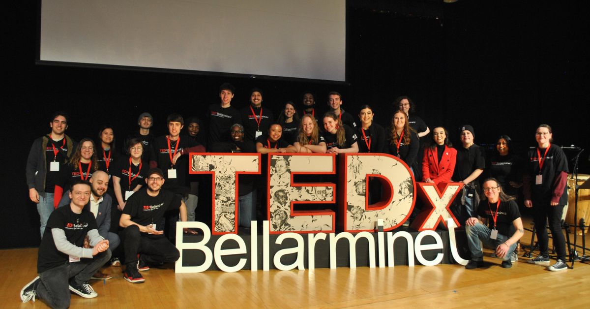 a large group of people beside a TedX sign