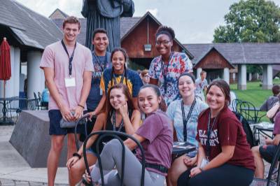 students sit at a table in the quad and pose for a photo