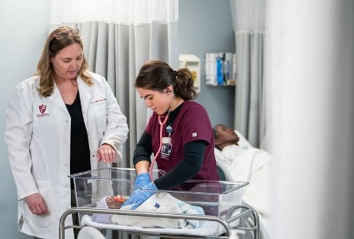 A nursing instructor works with a student in the simulation lab