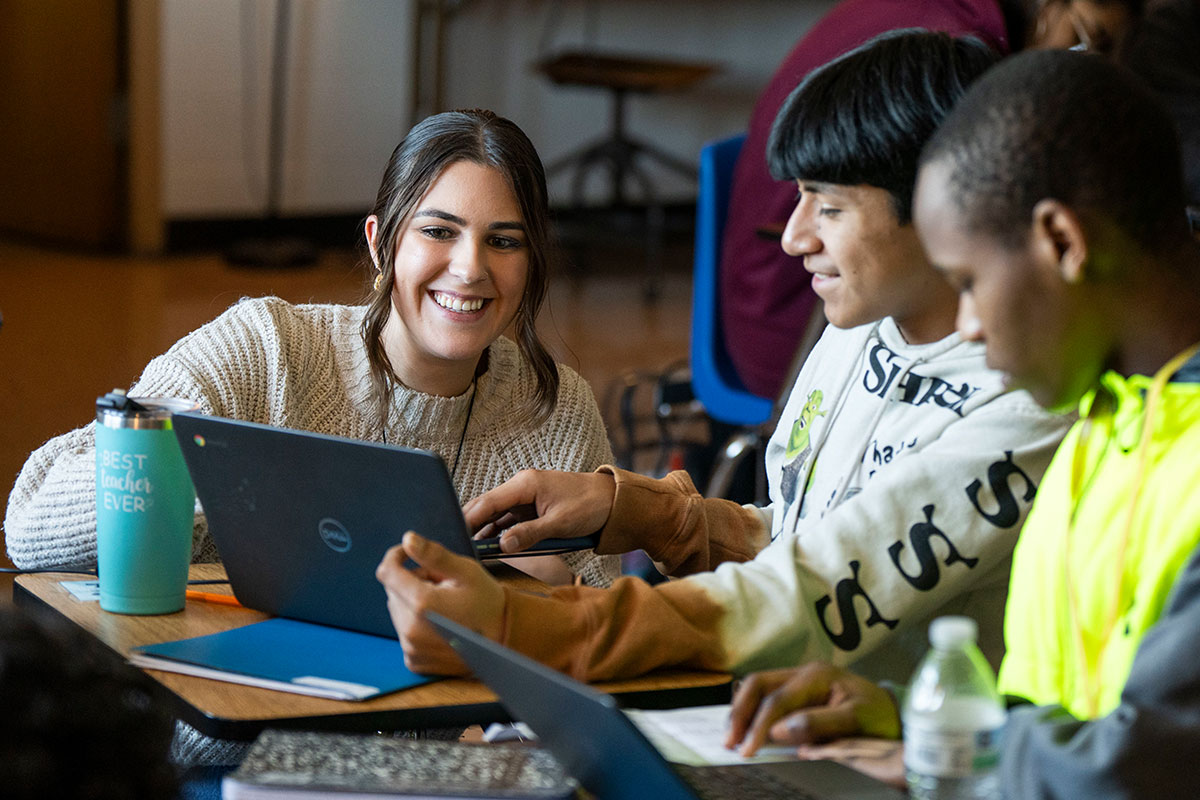 teacher smiles with students reading books